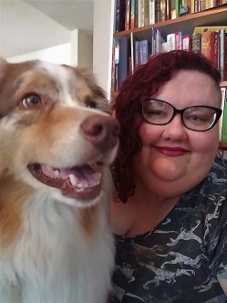 Erin sitting next to her dog with books in the background