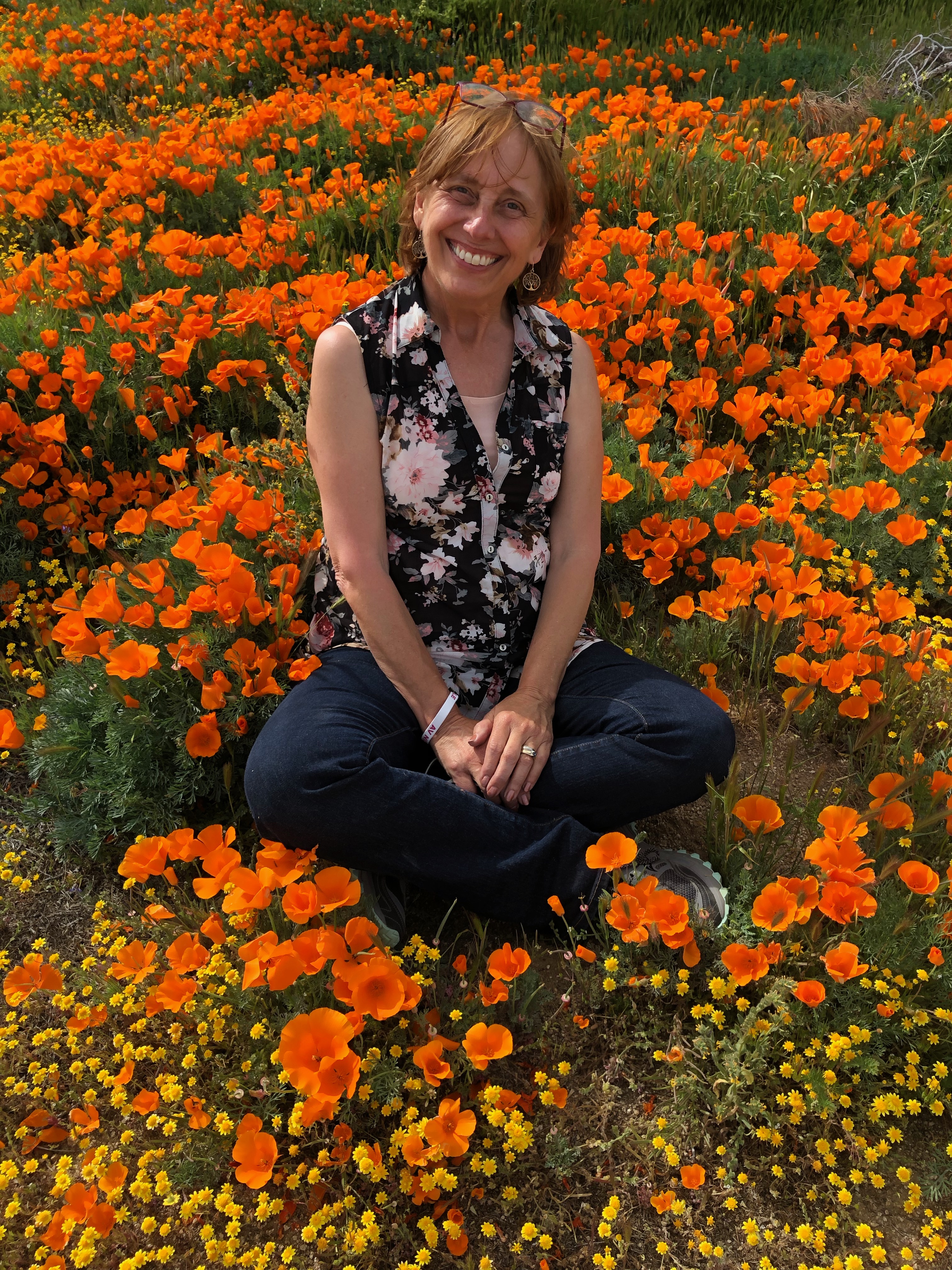 Mary sitting among golden CA poppies on a sunny day