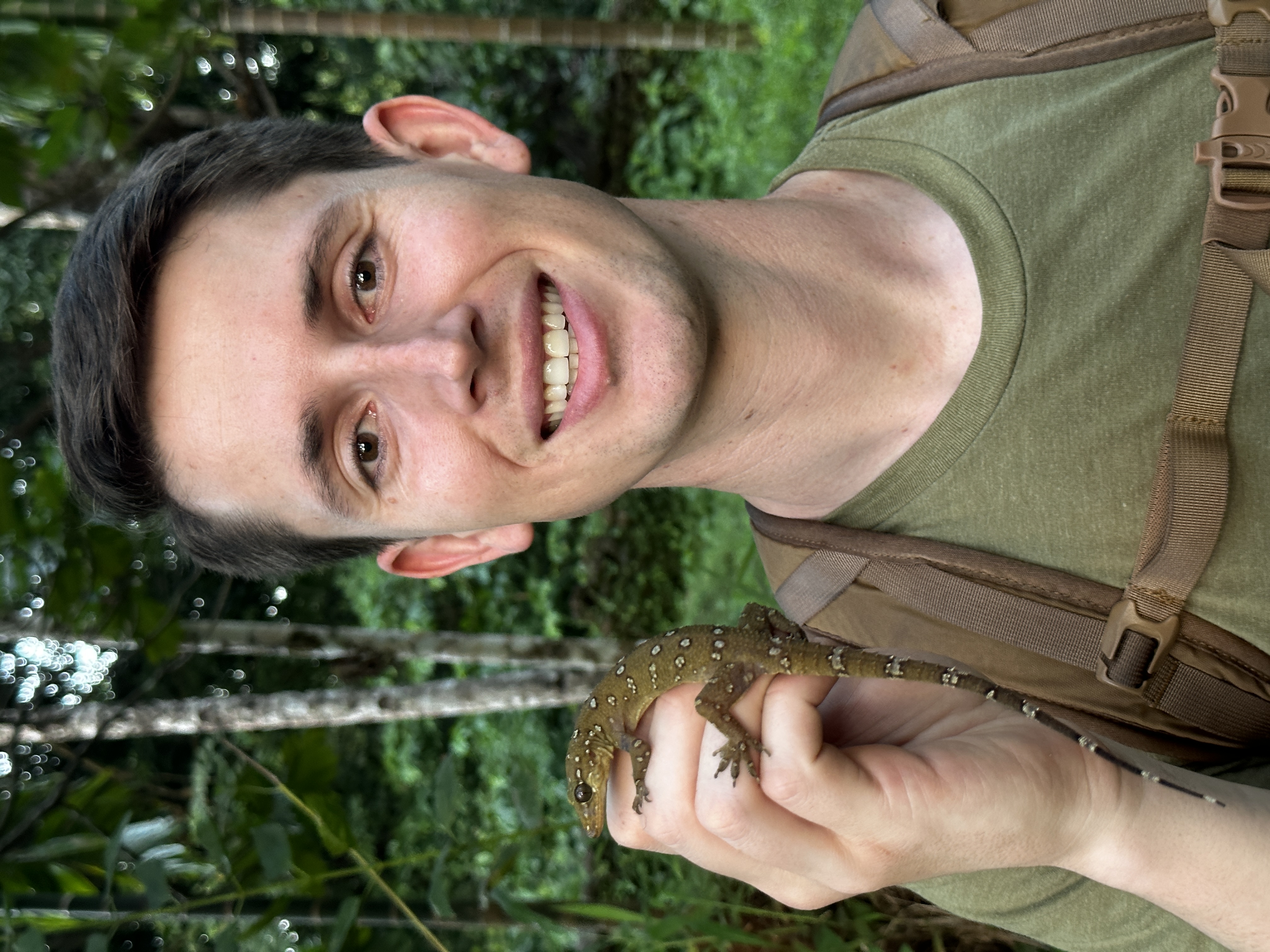 The instructor holding a gecko in the rainforest.