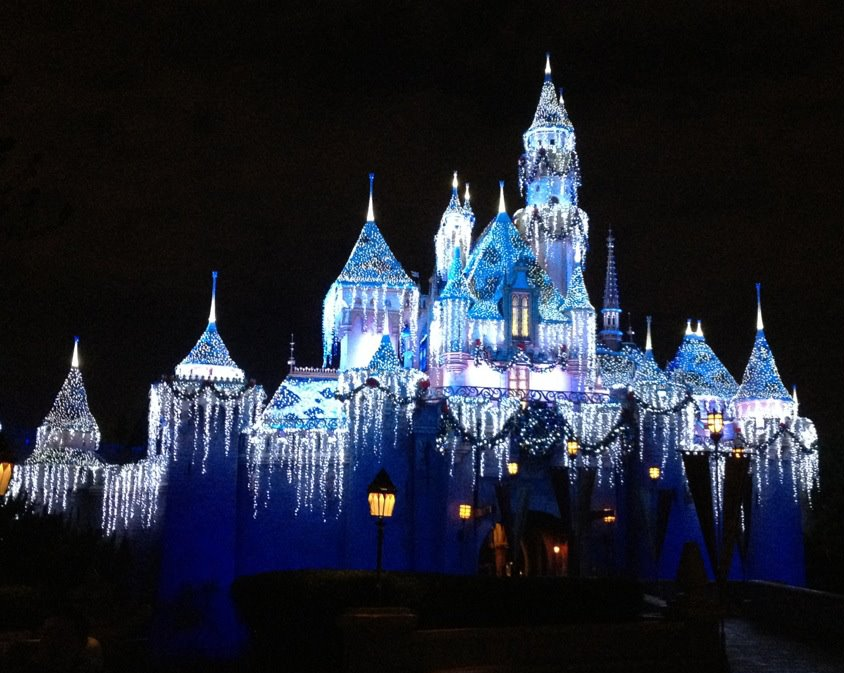 Castle at Disneyland covered in blue icicle lights at the holidays