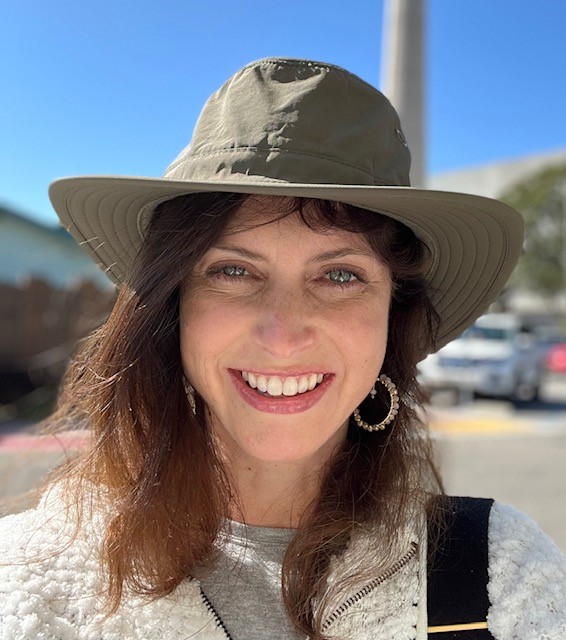 Instructor Jessica Edmond smiling, brown hair, blue eyes, wearing a green hat 
